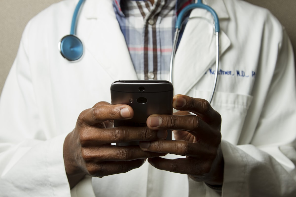 Profissional de saúde com estetoscópio consultando o celular
